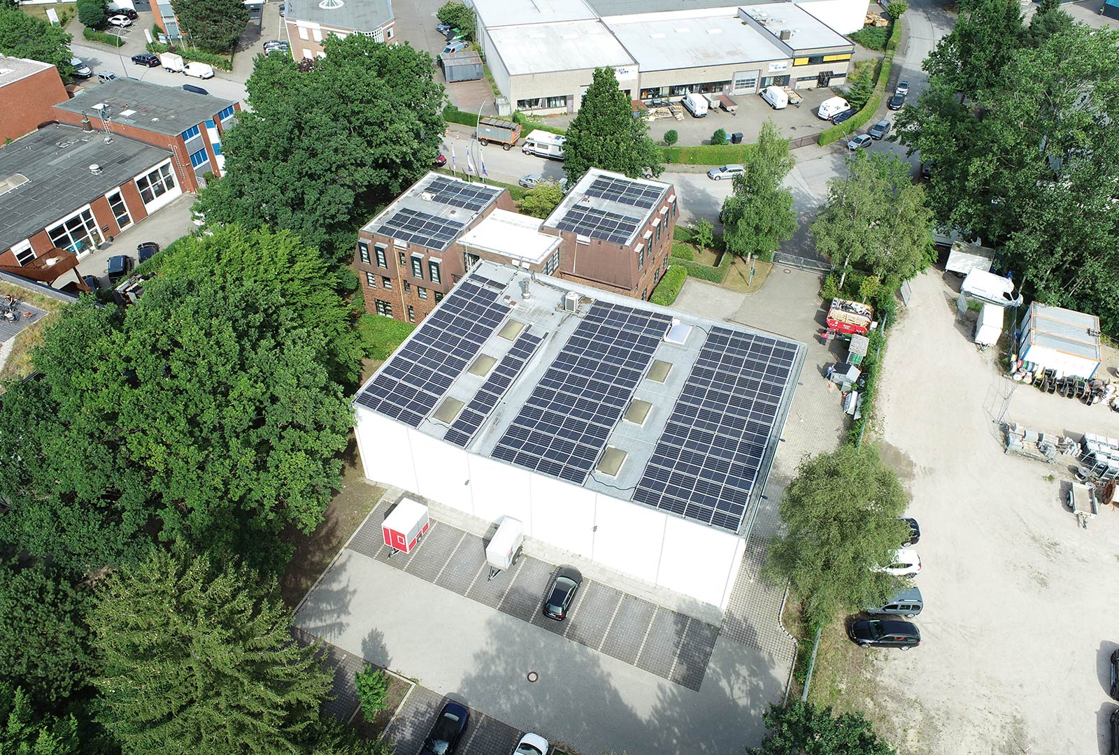 Kleines Bürogebäude mit PV Anlage auf dem Dach aus der Luft fotographiert