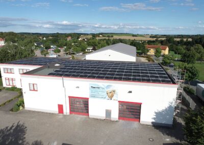 PV Anlage auf dem Flachdach einer Gewerbefläche im Hintergrund Felder und blauer Himmel